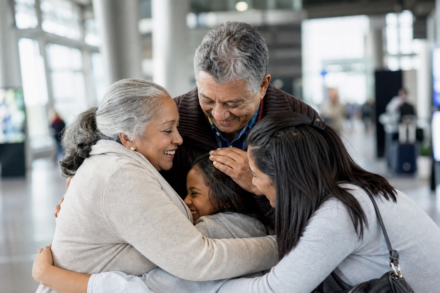 A family hugging in an airport arrivals area.